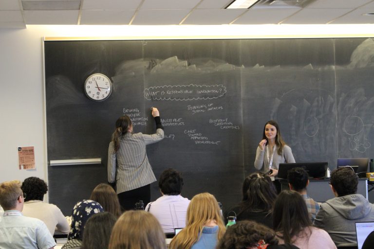 PhD students Alexi Orchard and Rebecca Kain describe responsible innovation to a room full of students.